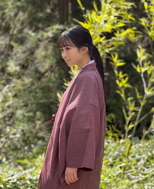 一位穿着粉色和服的女性侧身微笑于竹林背景中，展现出清新自然的气息。