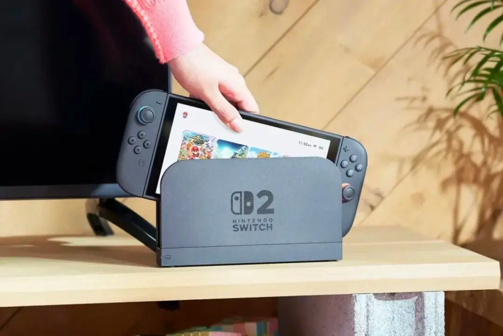 一位玩家正在將任天堂Switch 2遊戲機插入底座,顯示畫面為遊戲選單。