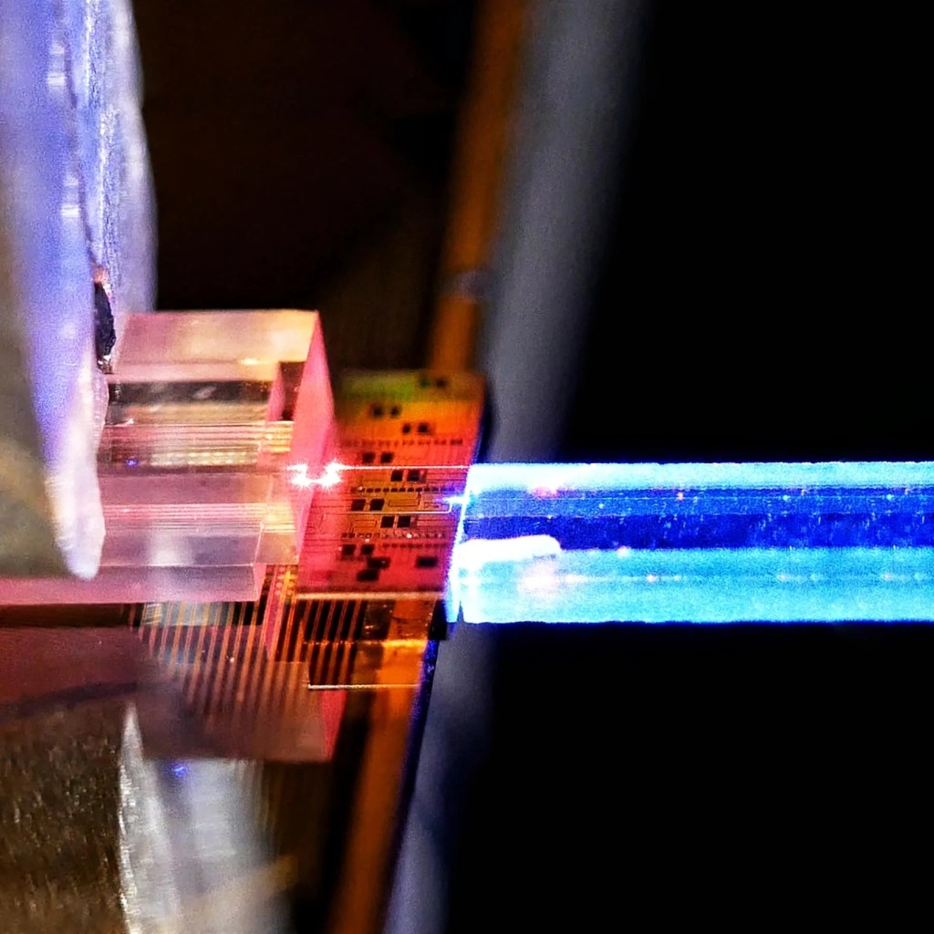 一個近距離的照片，展示了一個量子通訊設備，由光學元件和光纖組成，著重於光的傳輸過程。