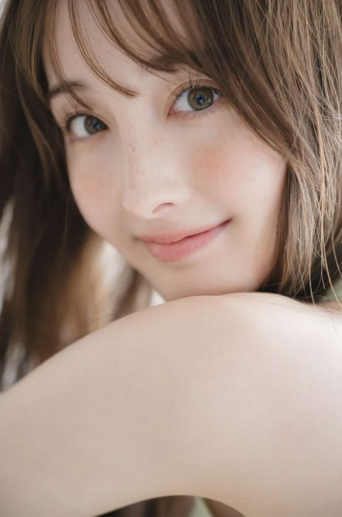 A close-up portrait of a young woman with long hair and soft features, smiling gently at the camera.