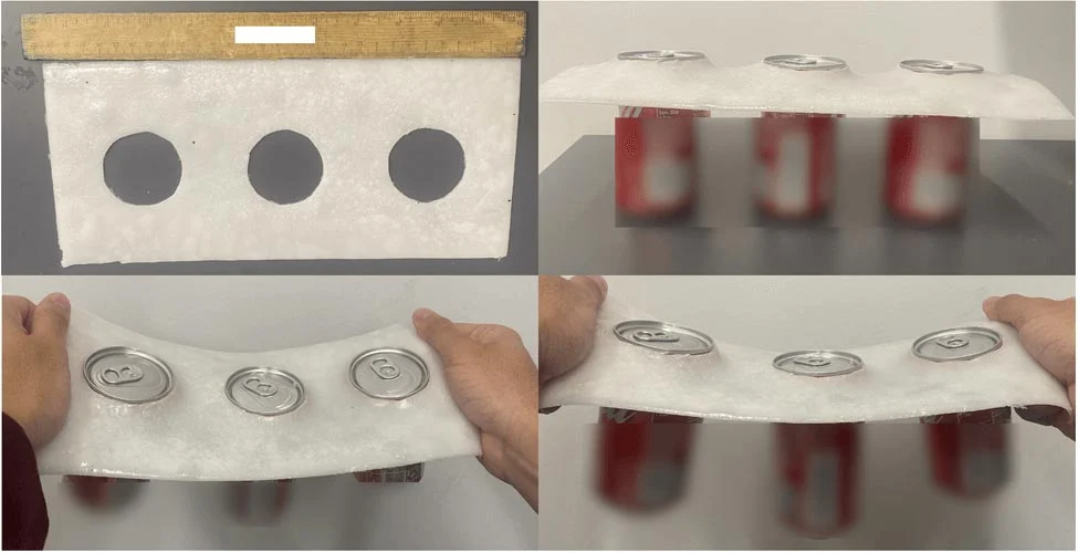 一種新型可生物降解的塑膠替代品樣本，展示了其形狀和強度，背景是一個平面，有三個飲料罐在下方，並用透明材料覆蓋，展示了如何支撐物品。