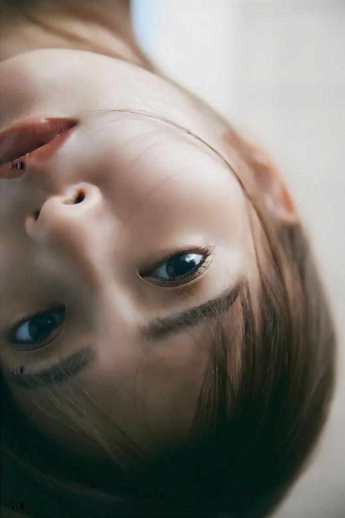 Close-up of a woman's face with long hair, looking directly at the camera while slightly tilted.