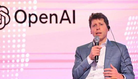 Sam Altman, CEO of OpenAI, speaking at an event with the OpenAI logo in the background.