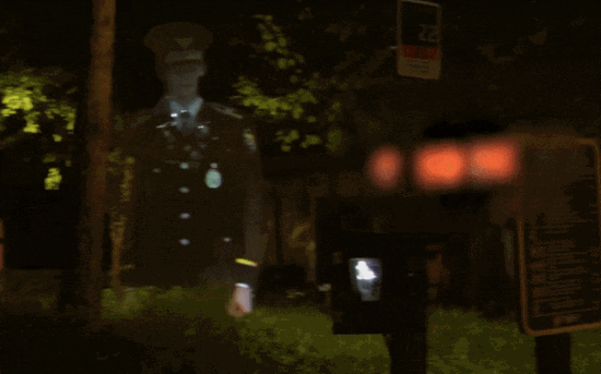 虛擬警察的3D全息投影在公園中站立，身穿警服，周圍環境昏暗，形成了一種神秘的氛圍。