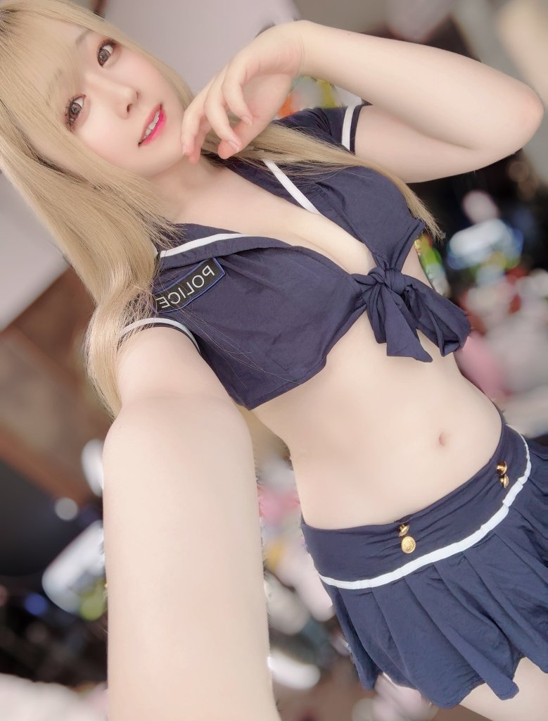 一个穿着海军风格警察服装的年轻女性自拍，背景模糊，显示出房间的其他物品。