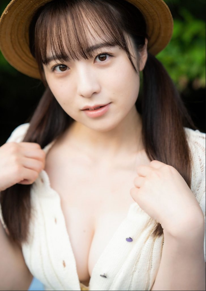A person with long dark hair wearing a straw hat and a light-colored cardigan, looking directly at the camera with a gentle expression.