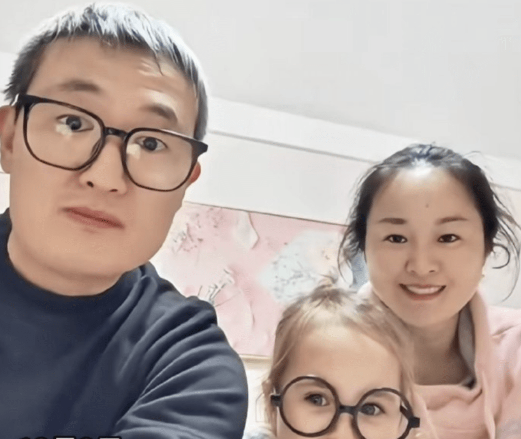 一對中國父母和他們的金髮碧眼的混血寶寶一起自拍，背景是簡約的室內環境。