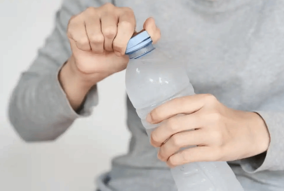 一隻手握住瓶子，另一隻手正在打開水瓶蓋。