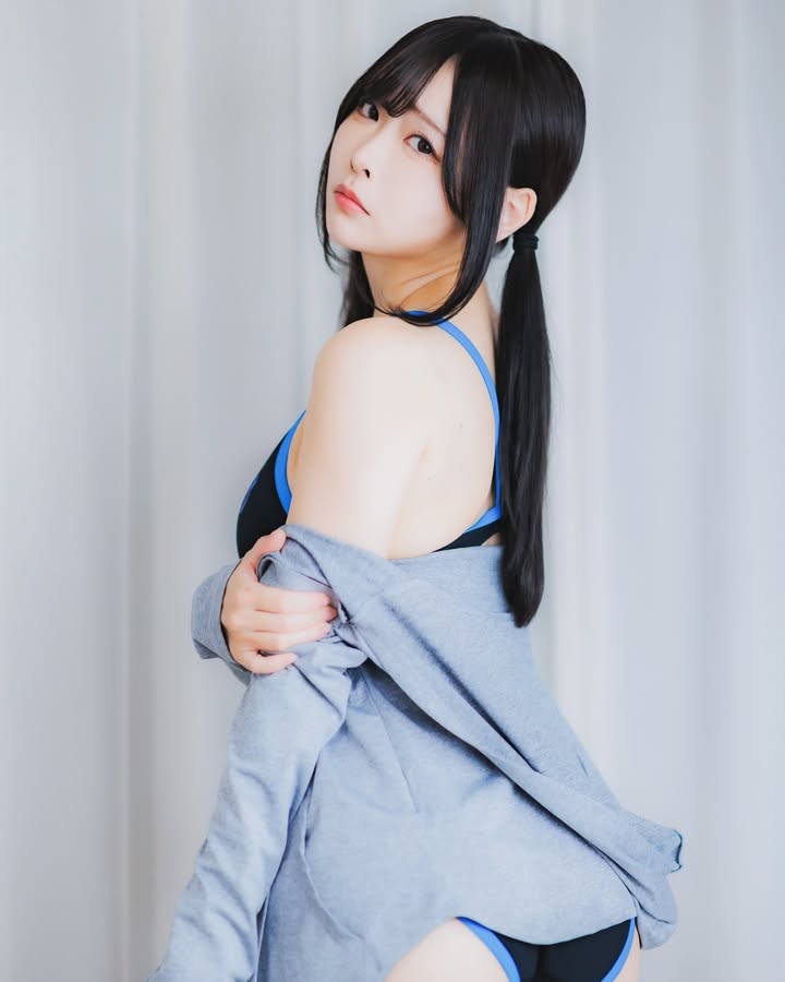 一名女性穿著運動內衣，搭配淺灰色外套，側身面對鏡頭，展現自信的姿態。