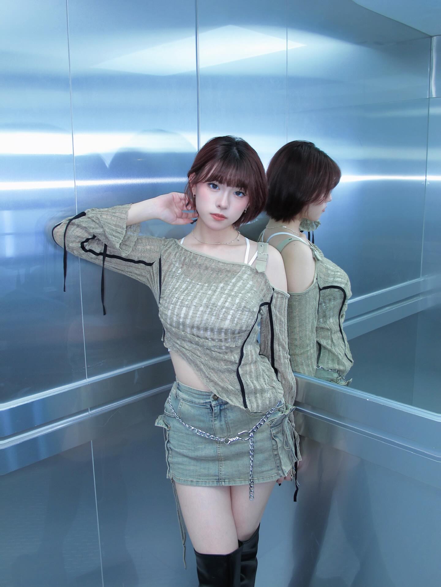 一位女性穿著褶皺的休閒服和短裙，站在鏡子前，展現出時尚造型。