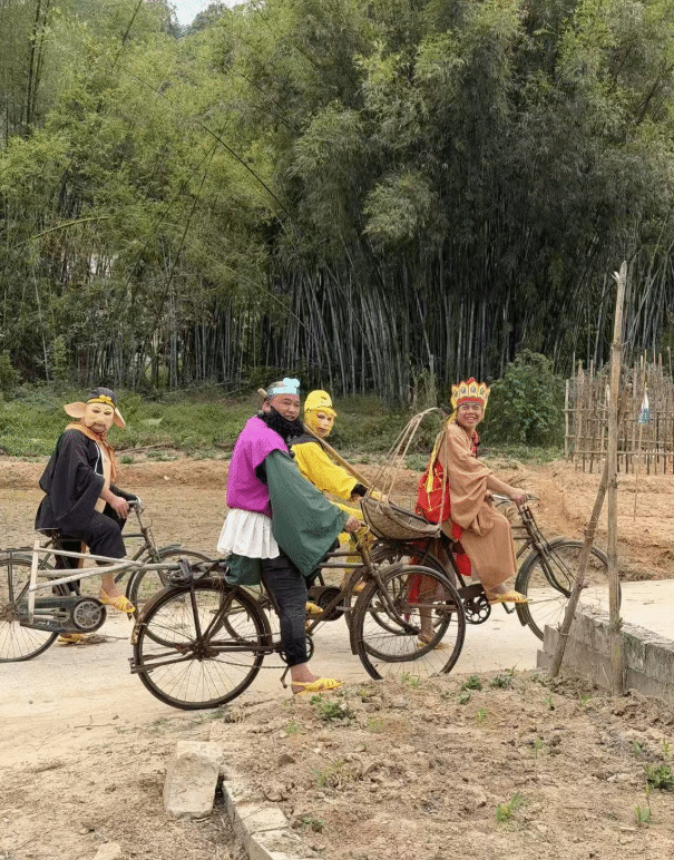 四位穿著特殊服裝的人騎著自行車，背景是竹林。
