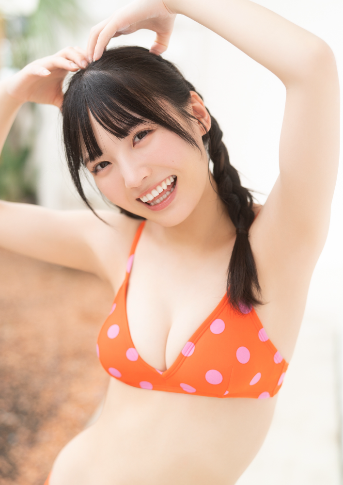 一位穿著橙色波點泳衣的女性微笑，擺出可愛的姿勢