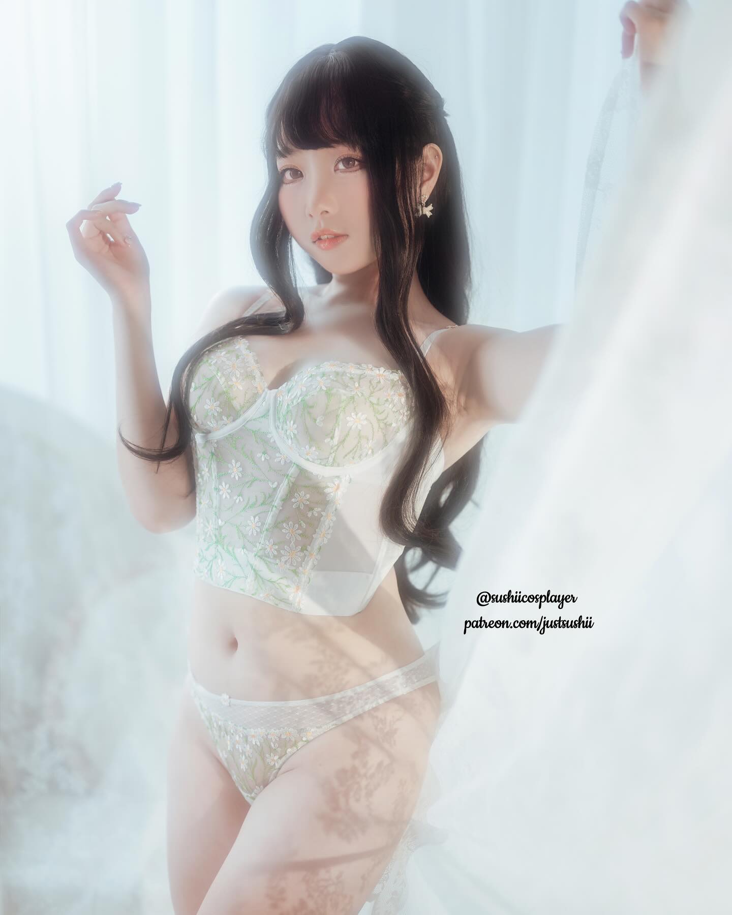 一位女性穿著精緻的內衣，站在柔和的光線中，背景模糊，顯示出淡雅的氛圍。