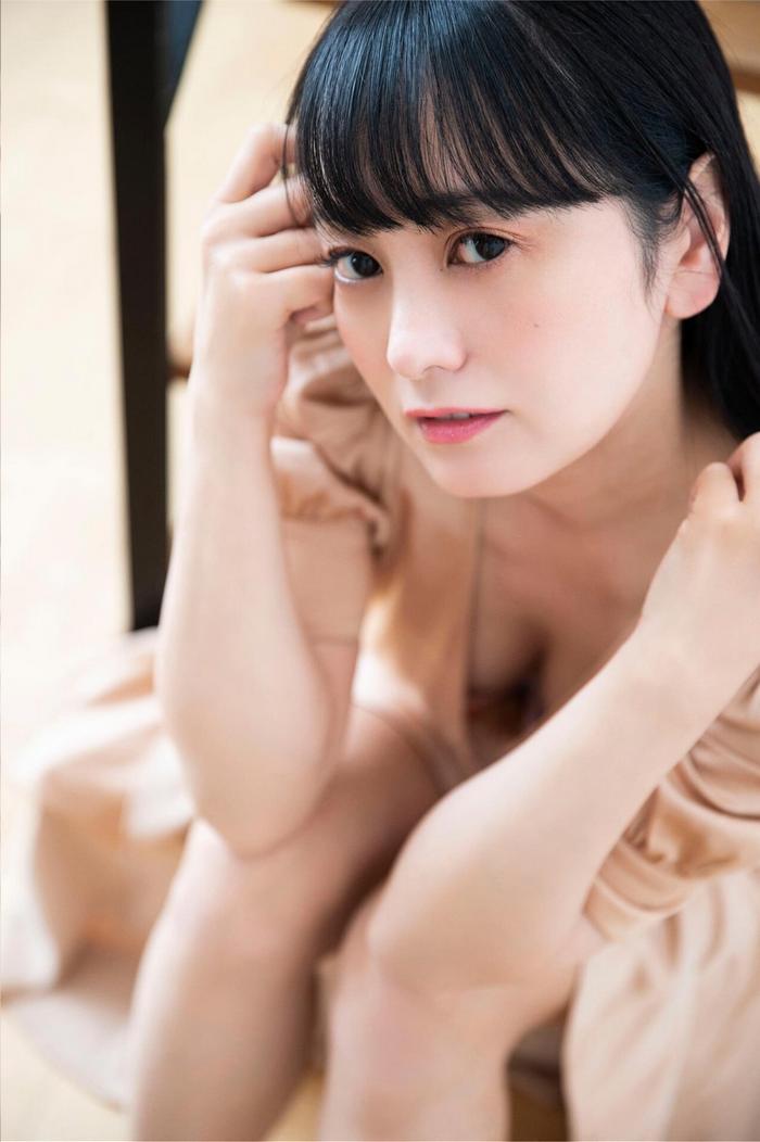 一位女性坐在地板上，穿著淺色衣服，手撫摸著自己的頭髮，表情溫柔。